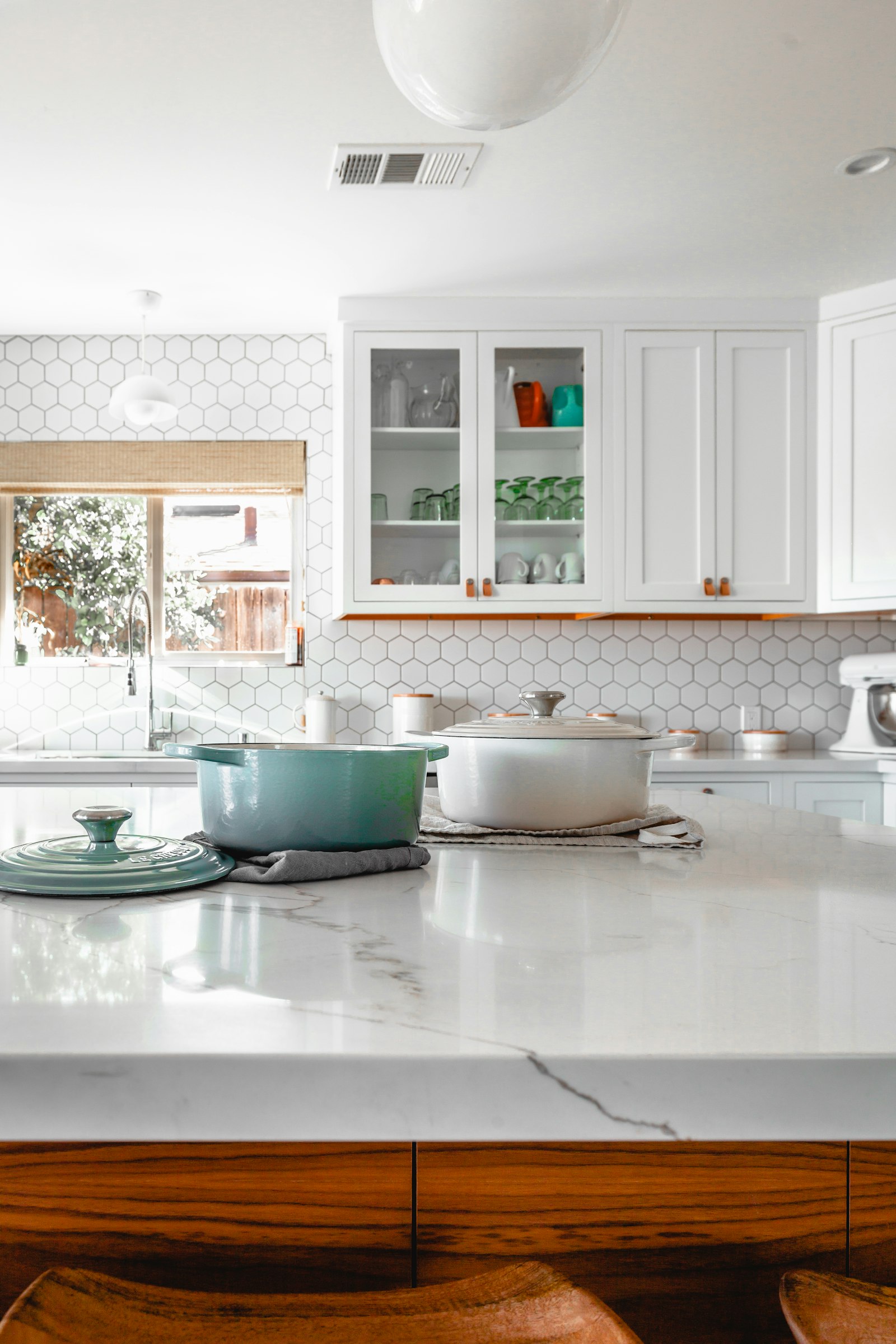 White kitchen cabinets above a marble island