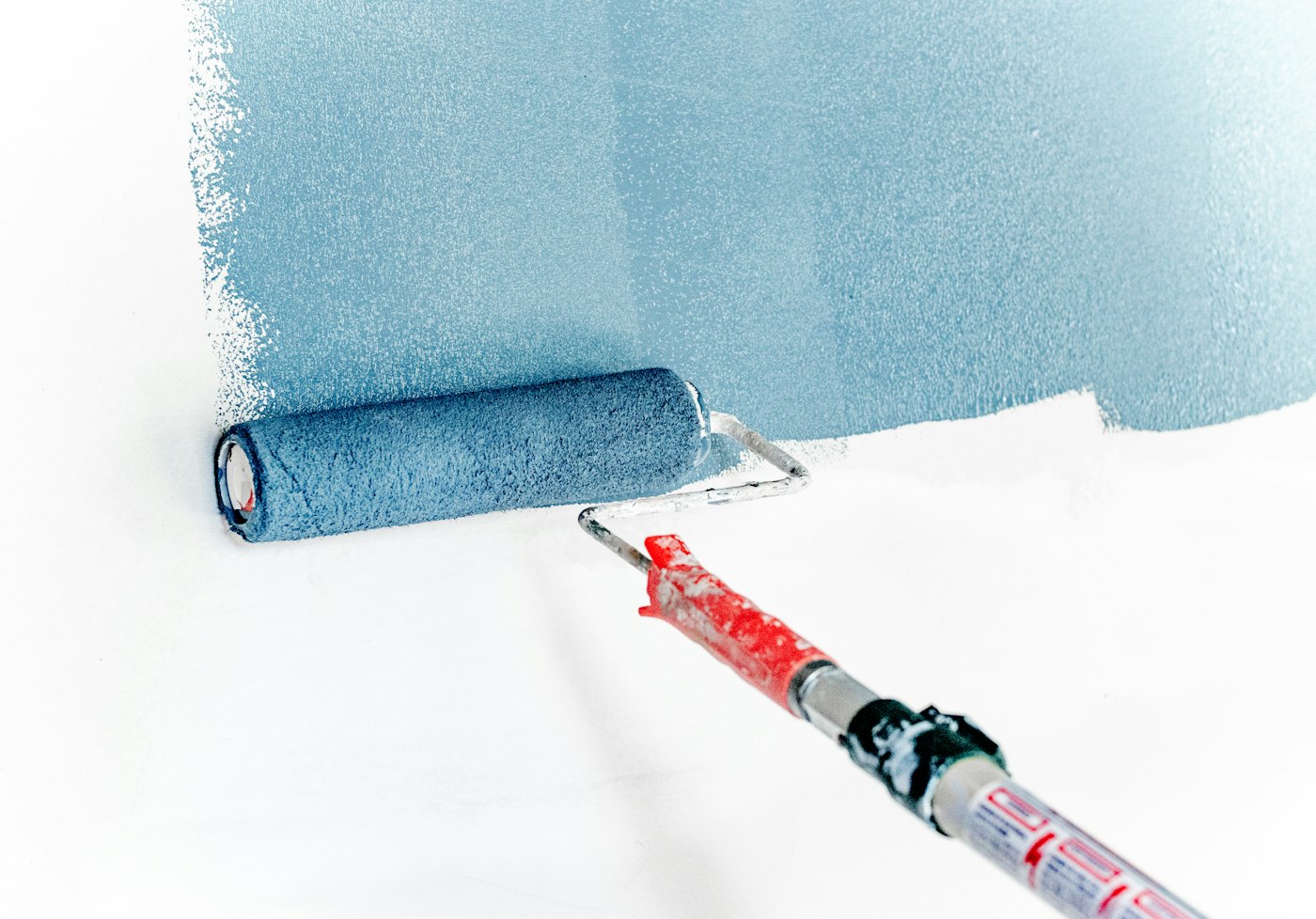 Close view of a roller applying blue-gray paint